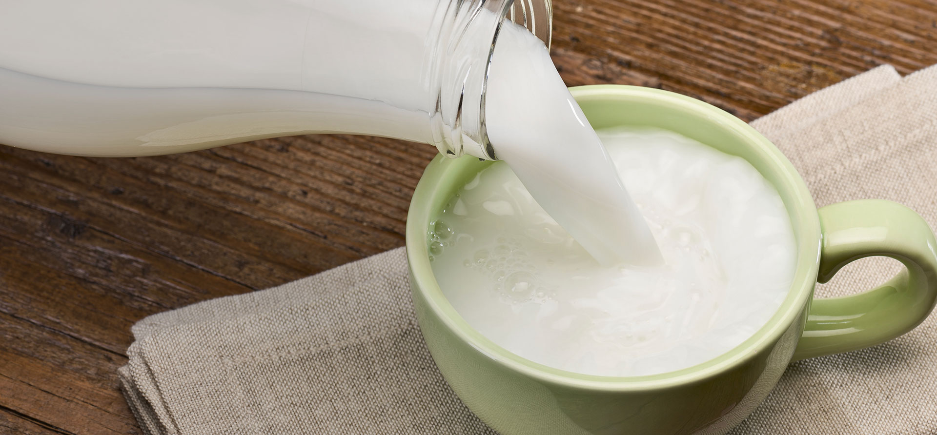 immagine di latte versato da bottiglia di vetro in tazza grande