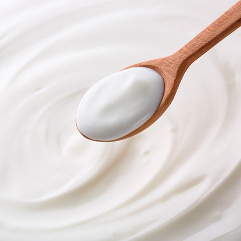 cucchiaio di legno con yogurt su sfondo di yogurt bianco