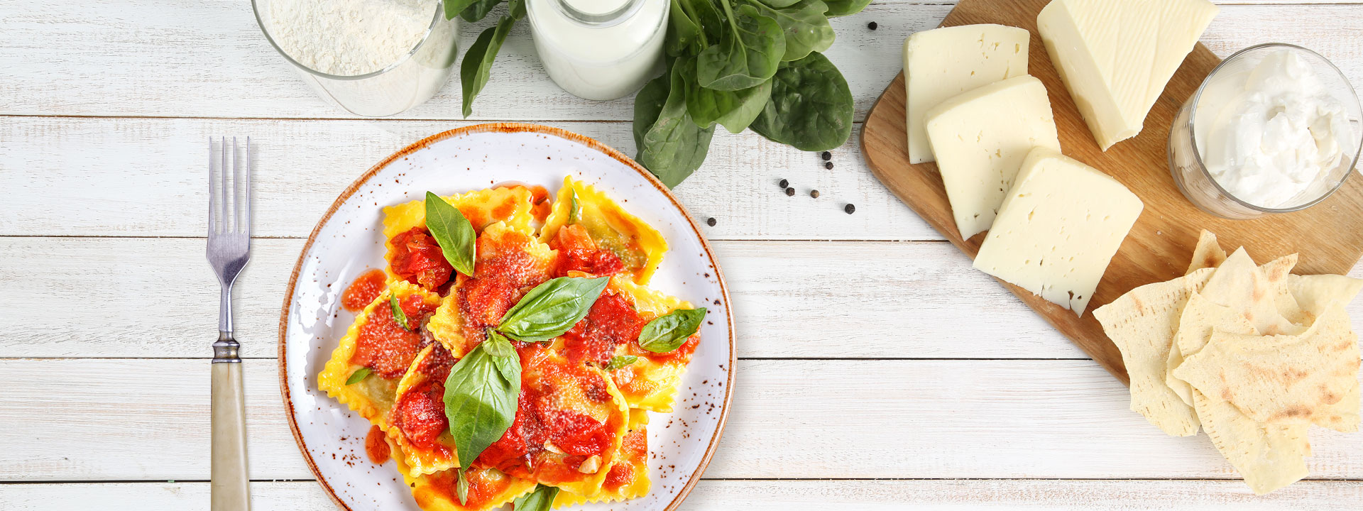 Piatto di ravioli di ricotta su tavola con formaggi vista dall'alto