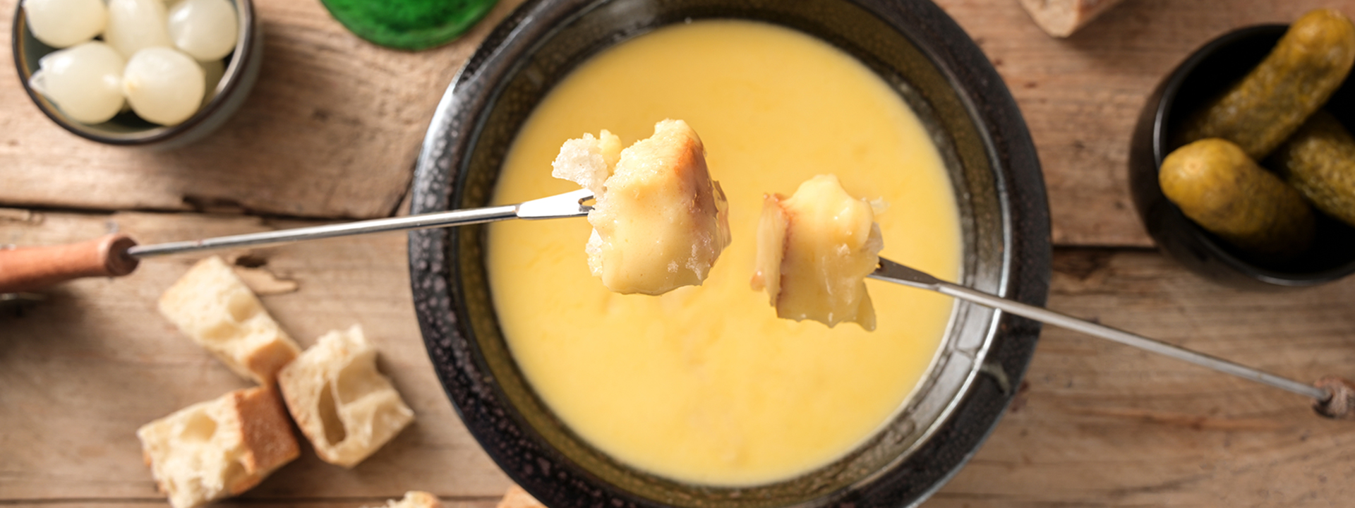 ciotola di fonduta di formaggio con pezzi di pane intinti su forchettine