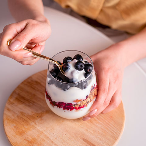 mani di donna con cucchiaio in dessert allo yogurt