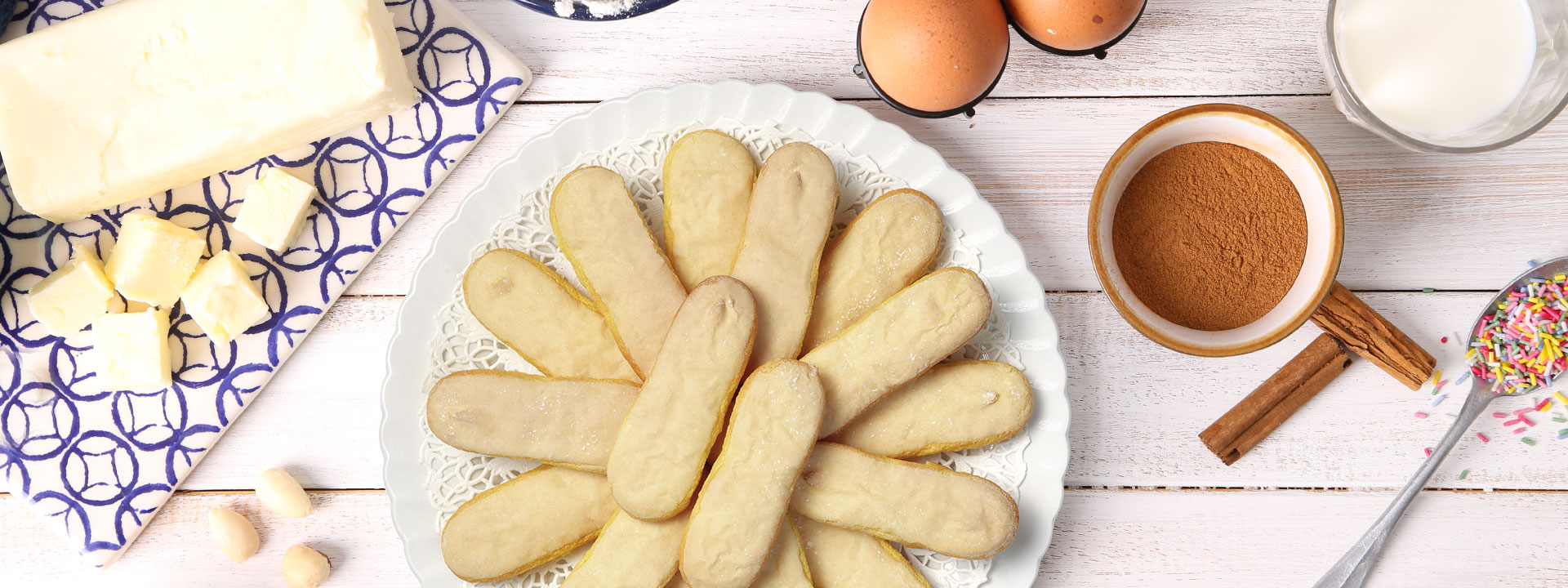 piatto di biscotti savoiardi su tavola con burro e ingredienti