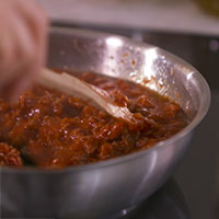 padella di sugo, con mestolo che gira, dettaglio