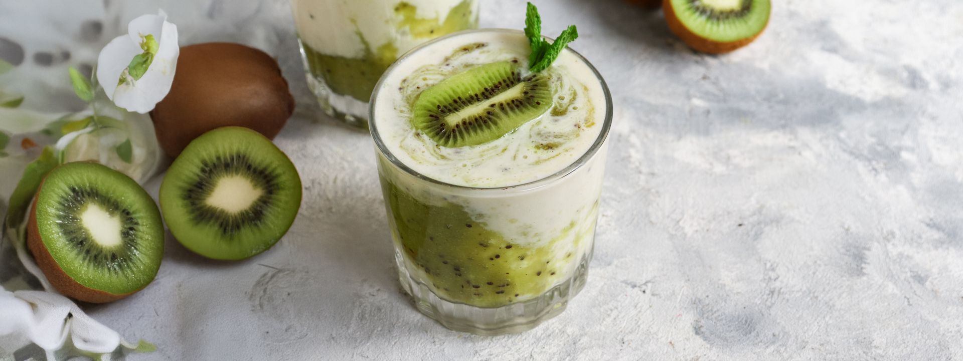 bicchiere di frappe al kiwi e kiwi tagliati a metà