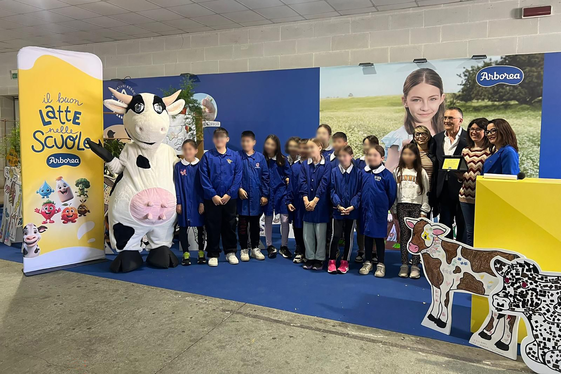 Bambini in grambiule in posa al termine del progetto Il buon Latte nelle Scuole con mascotte mucca