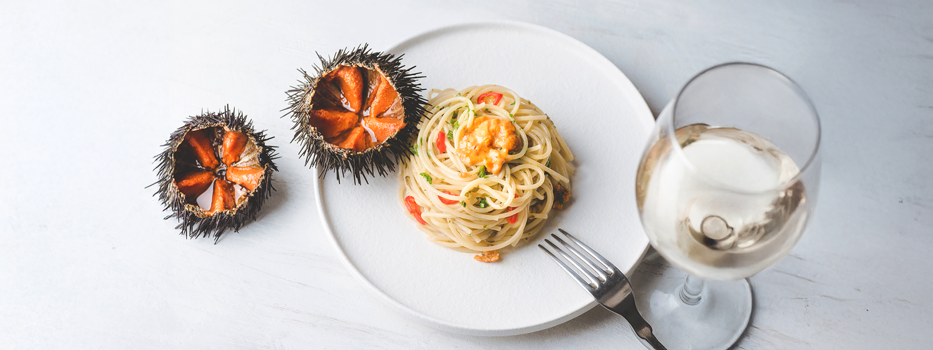 Spaghetti ai ricci di mare vista dall'alto con bicchiere di vino
