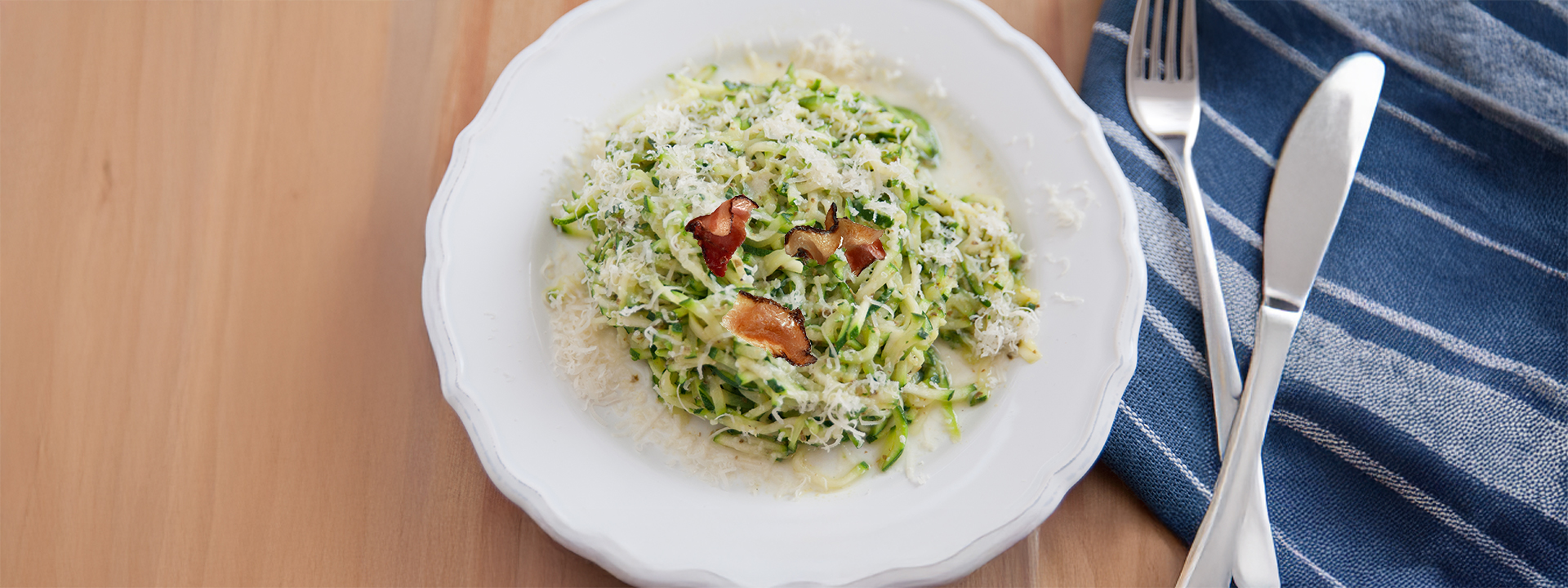 Piatto di spaghetti realizzati con zucchine crude, con uova, formaggio e pancetta