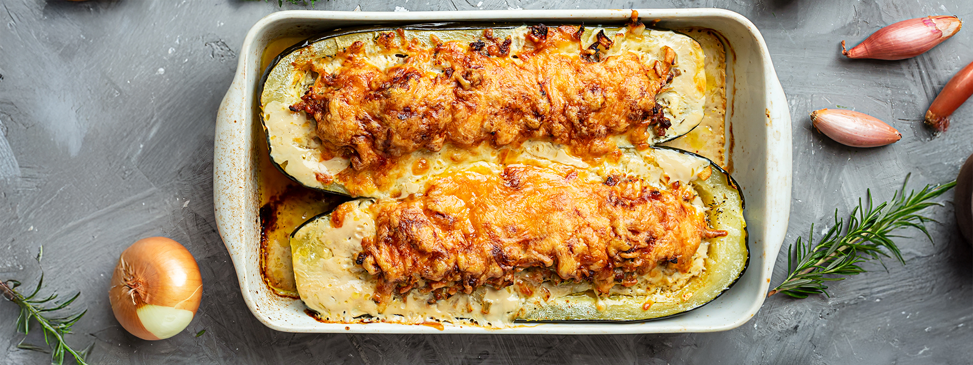 zucchine ripiene di formaggio e gratinate, teglia su piano scuro
