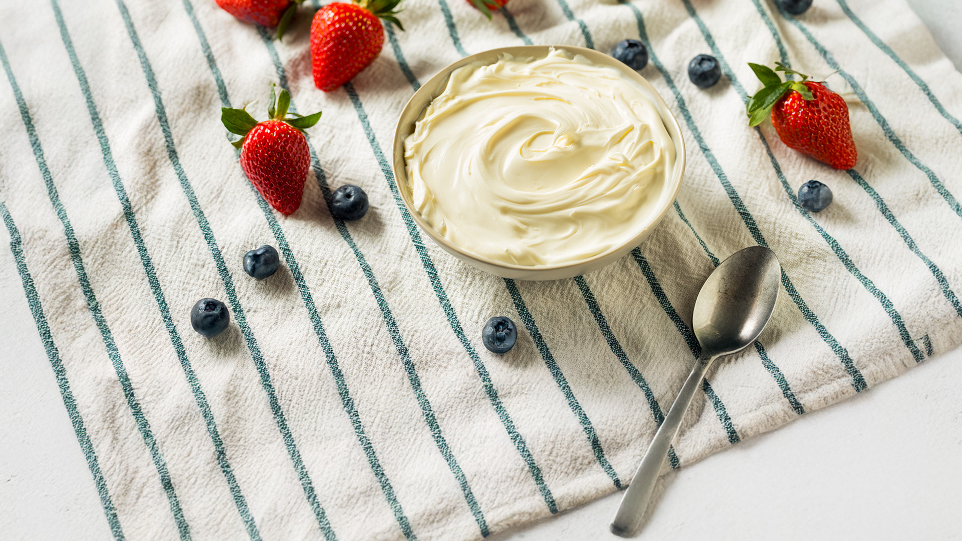 ciocola di mascarpone, cucchiaio e frutti di bosco su tovaglia a righe